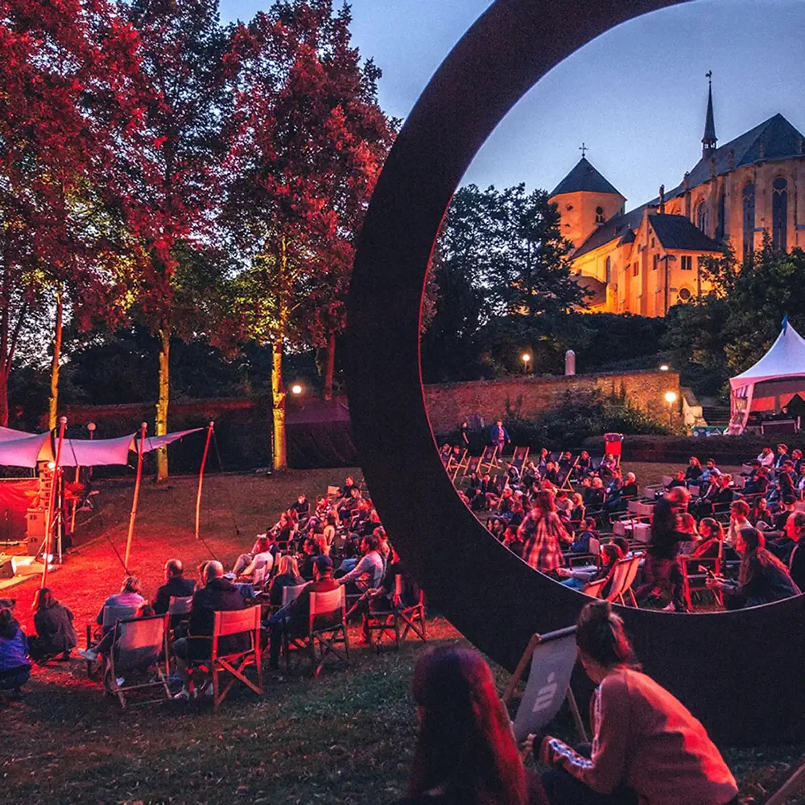 Open-Air-Konzert im Skulpturengarten Abteiberg bei Nacht, Festival Pop Paradiso mit beleuchteter Kirche im Hintergrund – ein Projekt von Vlip zur urbanen Belebung des öffentlichen Raums.