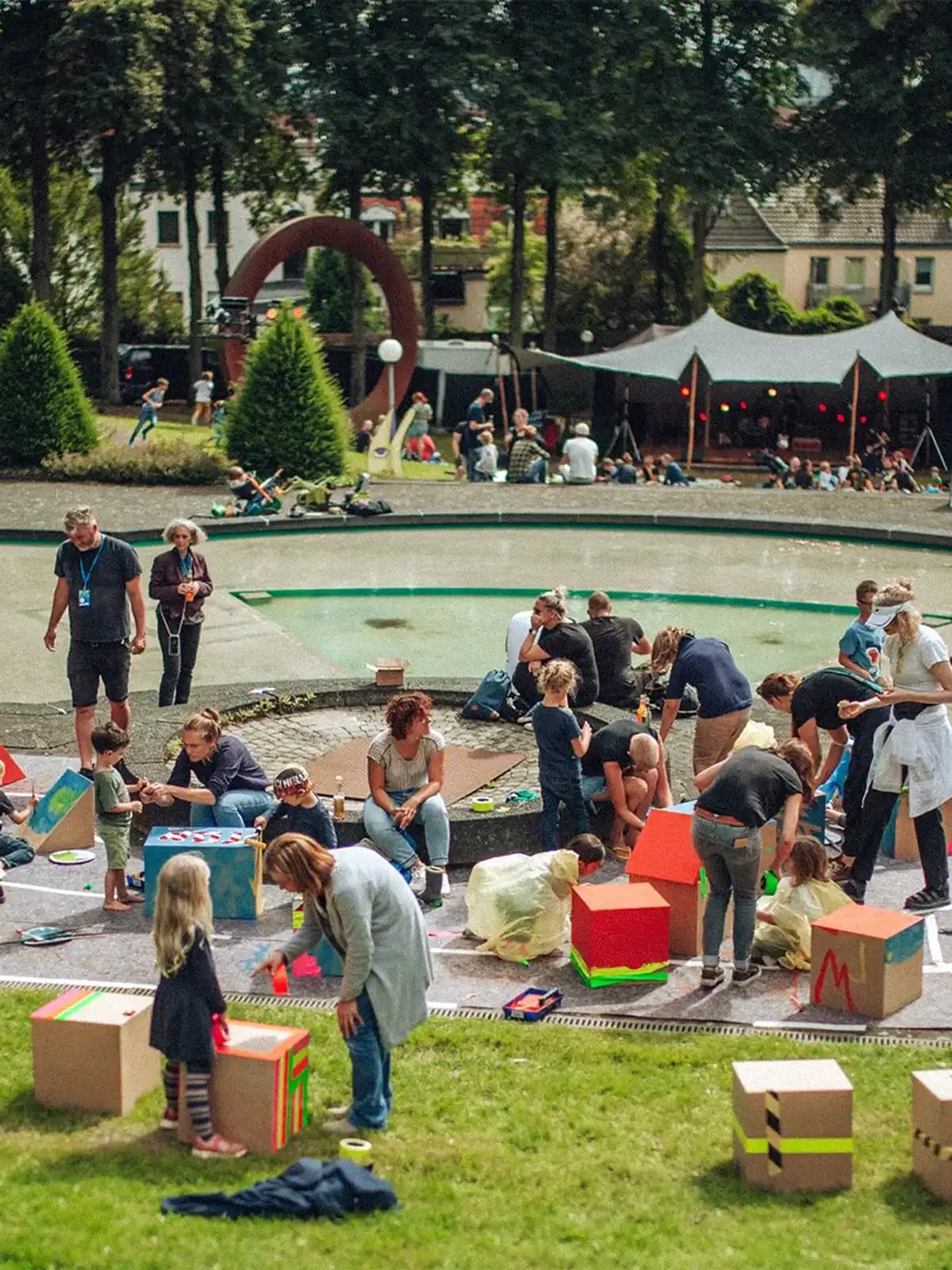 Kinder und Erwachsene gestalten bunte Kartons bei einem Workshop im Skulpturengarten Abteiberg während Pop Paradiso