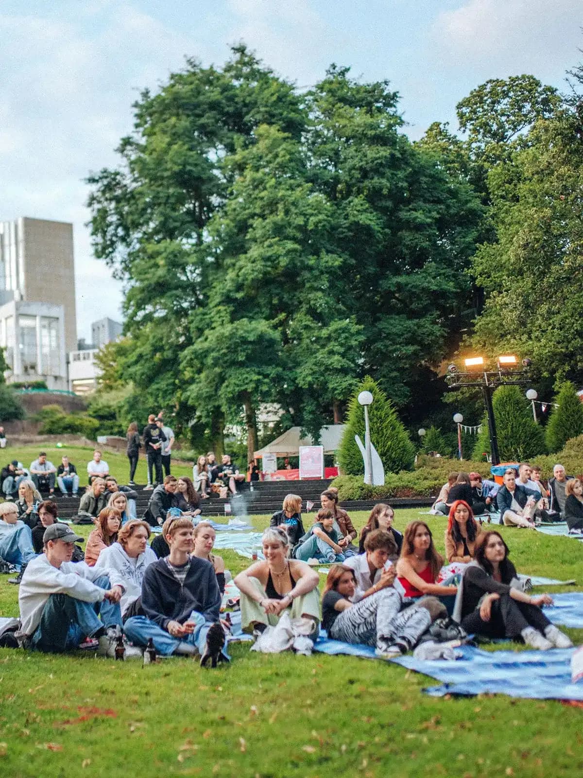 Besucherinnen und Besucher sitzen auf Decken im Skulpturengarten Abteiberg beim Festival Pop Paradiso