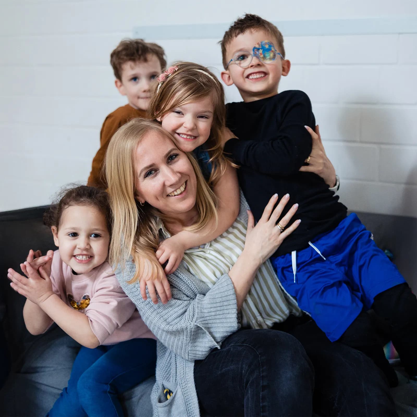 Eine Erzieherin sitzt mit mehreren Kindern lachend in einer Kita-Umgebung – pro multis Rebranding von VLIP.